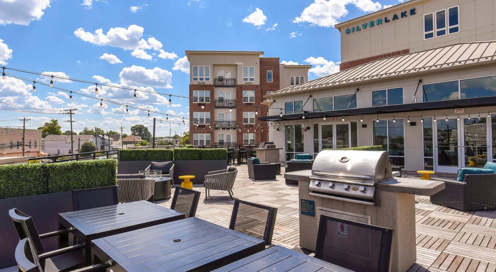 State-of-the-art amenities a grill area with tables and chairs in front of a building