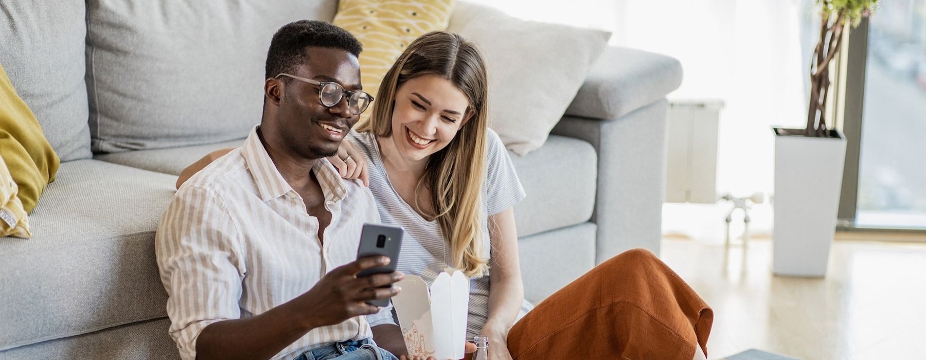 Find your perfect fit at SilverLake a man and woman with take out, sit against a couch on their living room floor and watch at their cell phone